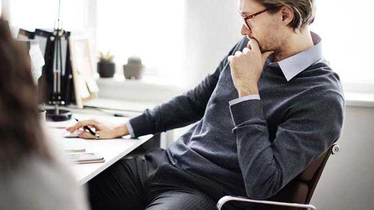 Business man sitting at desk thinking about a business disaster plan.