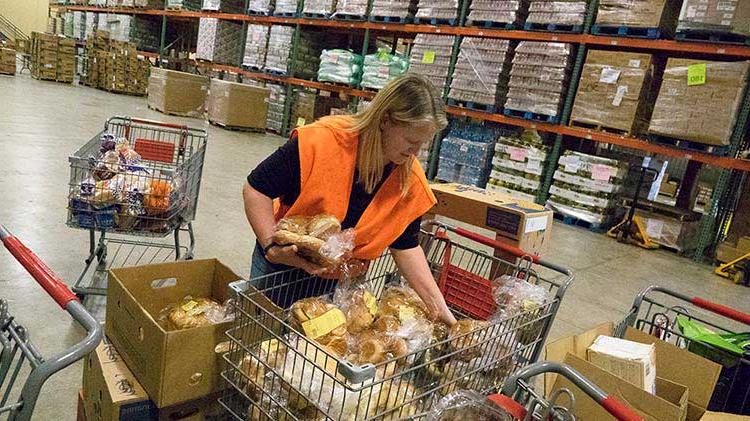 During Good Neighbor Day, a woman sorts food into boxes and baskets at a food pantry.