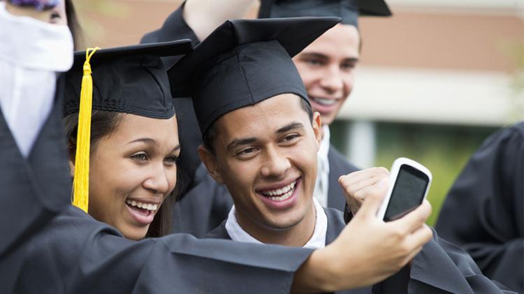 College graduates taking self-portrait together outdoors