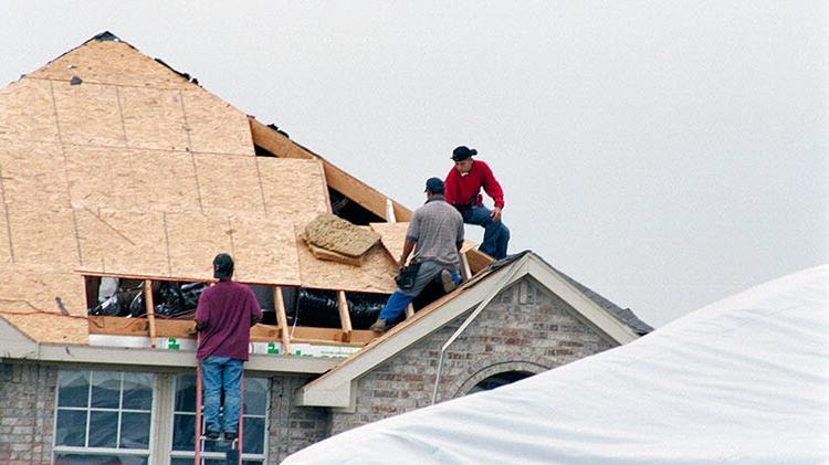 Contractors replacing a roof after storm damage.