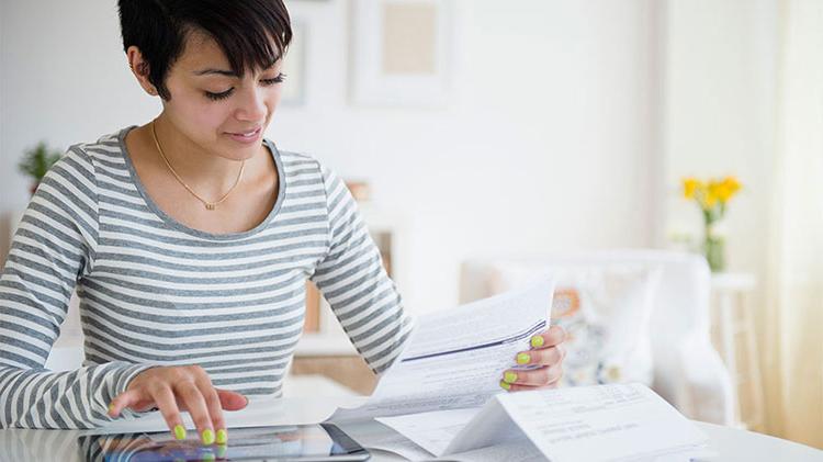 Woman sitting at table figuring out how to build a savings account.